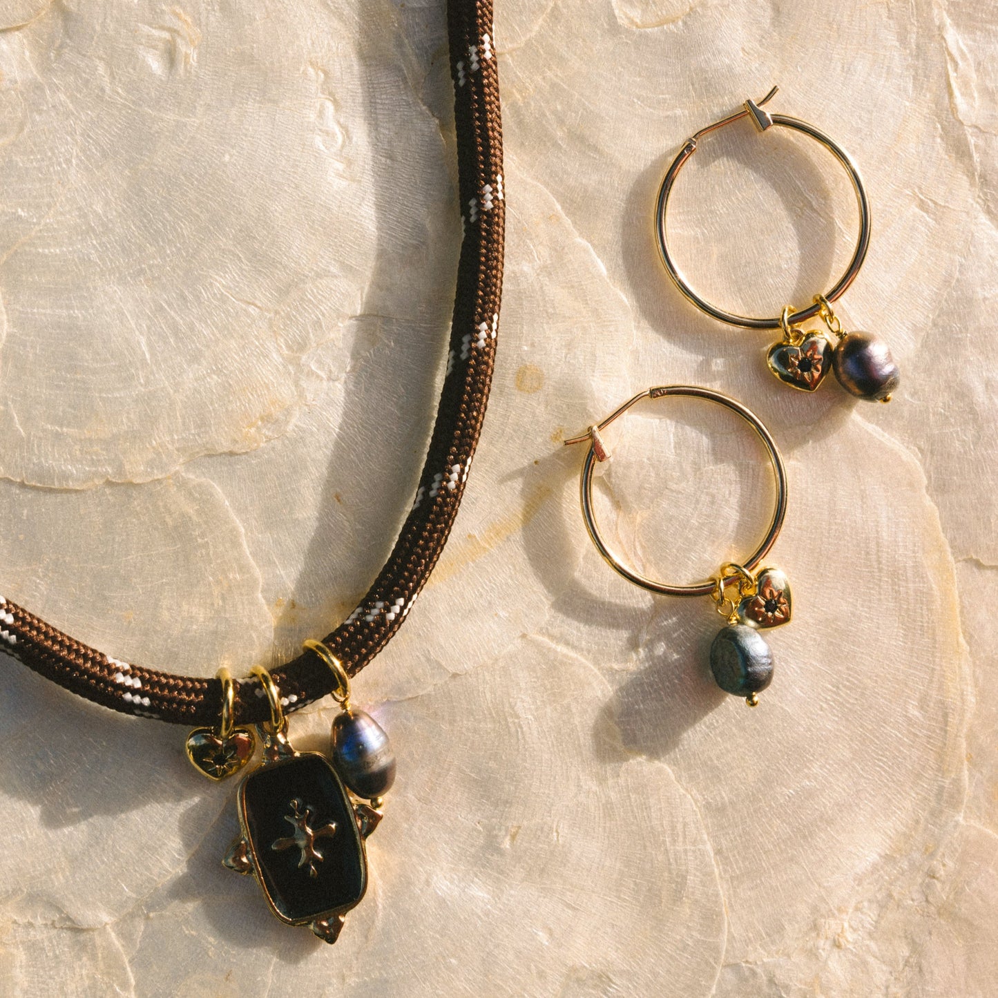 Necklace and hoop earrings with black and gold beads on a marble surface